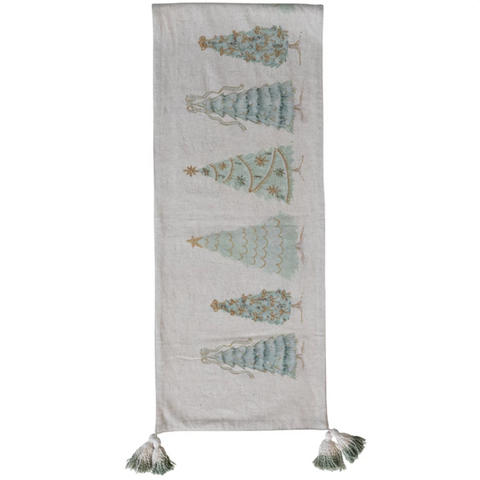 Textile with embroidered Christmas tree designs and tassels on a white background