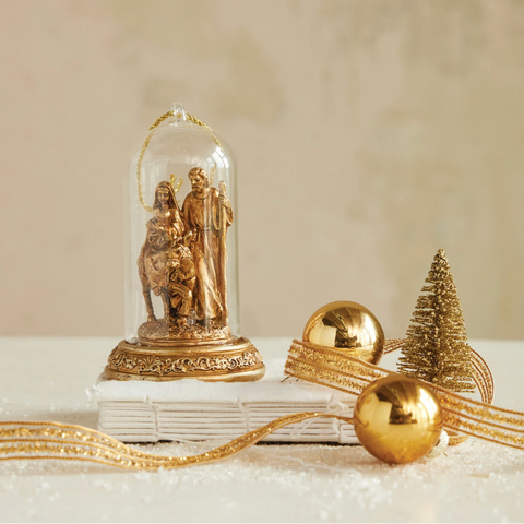 Decorative setup with gold figurines, ornaments, and a small tree on a beige background