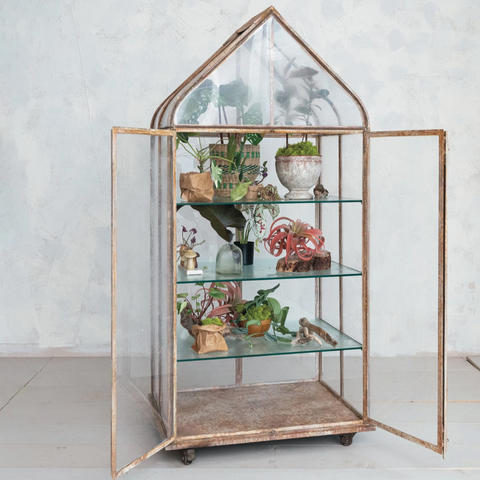 Decorative glass cabinet with wooden frame on a white floor and light gray wall background