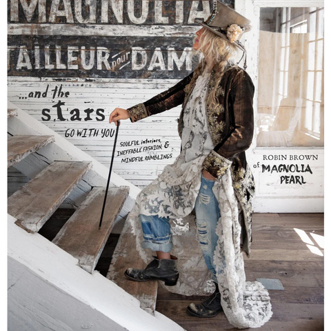 Person in a long, patterned coat standing on a staircase with a decorative wall in the background.