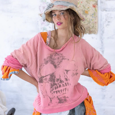 Woman wearing a pink sweatshirt with orange sleeves and a straw hat in a snowy setting