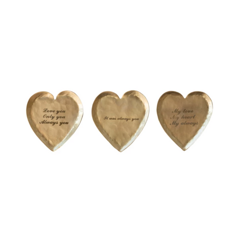 Three heart-shaped brass objects with engraved text on a white background