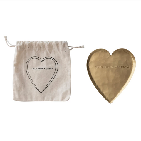 Heart-shaped brass object and drawstring bag with 'Once Upon a Dream' text on a white background