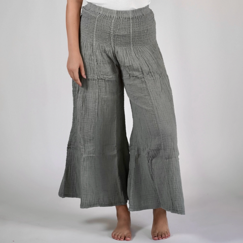 Person wearing gray checkered wide-leg pants and a white tank top on a plain background