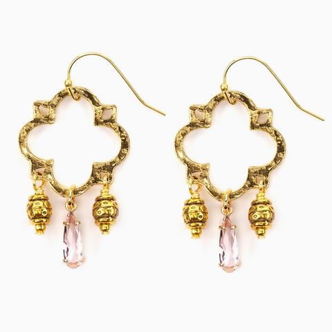 Gold earrings with pink gemstones on a white background