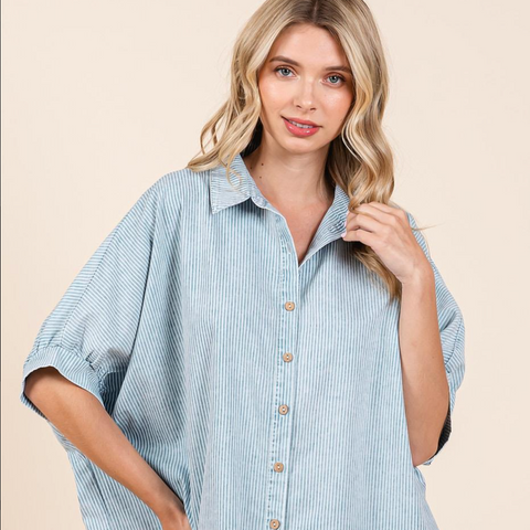 Woman wearing a blue and white striped shirt with a plain background