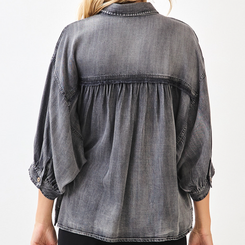 Person wearing a gray denim shirt on a white background