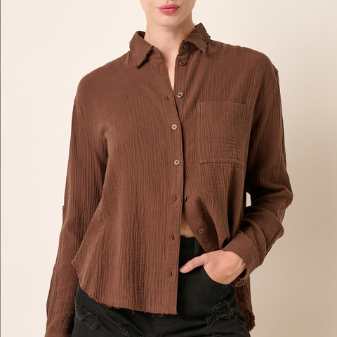 Woman wearing a brown ribbed shirt with a plain background