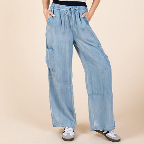 Woman wearing a striped sleeveless top and wide-leg denim pants on a beige background