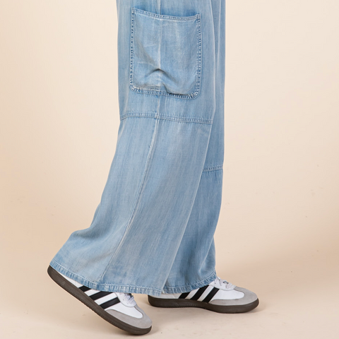 Light blue denim cargo pants worn by a person on a beige background
