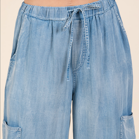 Light blue denim pants with a tie waist on a beige background