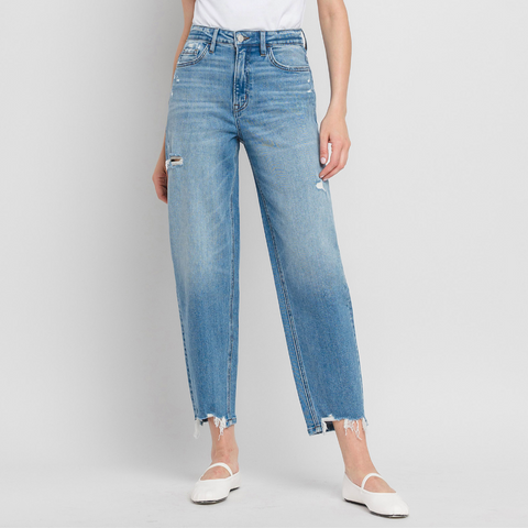 Person wearing light blue jeans and a white top on a plain background