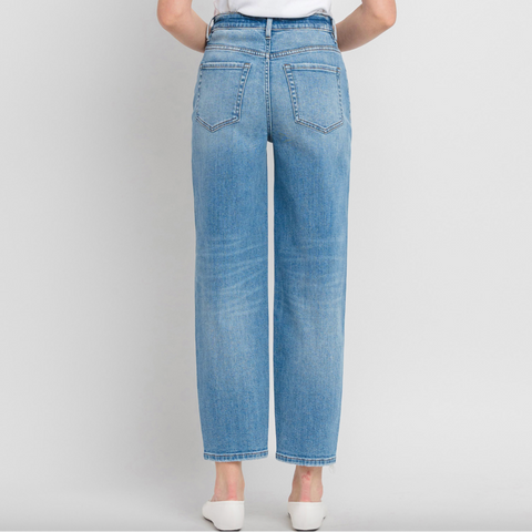 Person wearing light blue jeans and a white top on a plain background