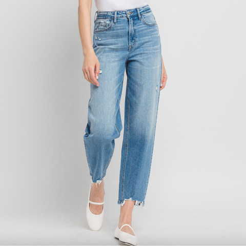 Person wearing light blue jeans and a white top on a plain background