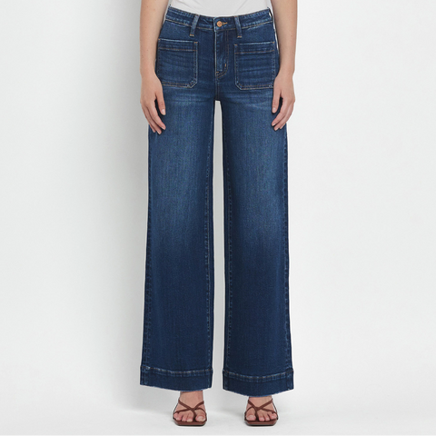 Person wearing blue wide-leg jeans and a white top on a white background