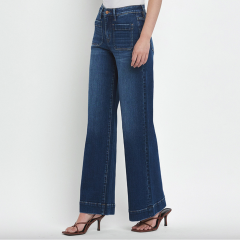 Person wearing blue jeans and a white top on a plain background