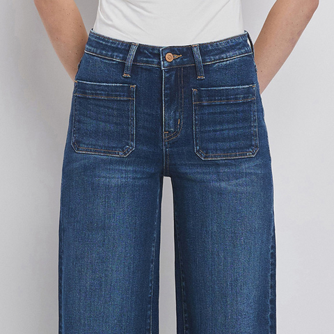 Blue jeans worn by a person on a plain background