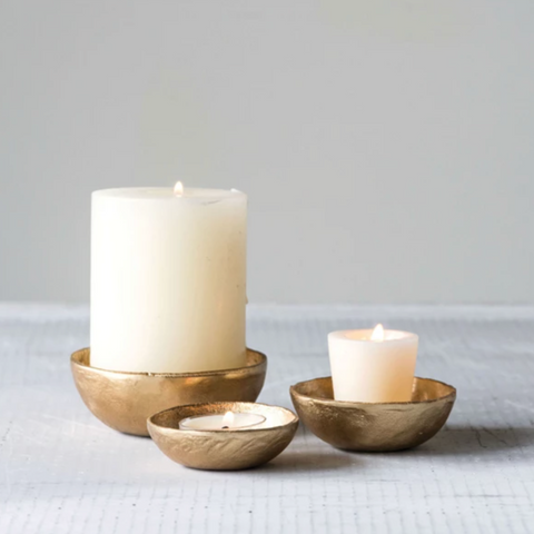 Three candle holders with candles on a light gray surface
