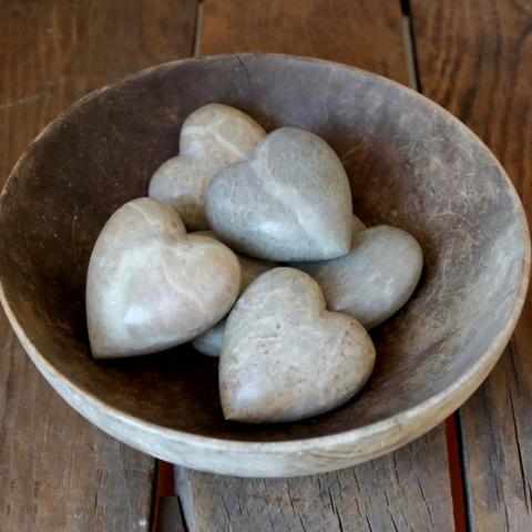 Heart-shaped stones in a wooden bowl on a wooden surface