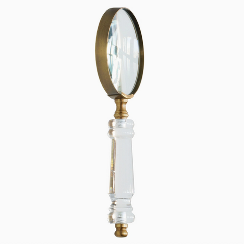 Vintage-style magnifying glass with a white handle and gold accents on a white background