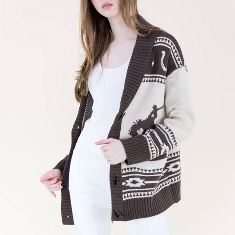 Woman wearing a patterned brown cardigan over a white top on a plain background