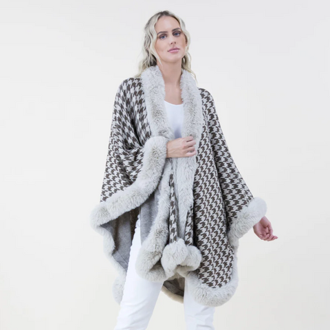 Woman wearing a patterned poncho with fur trim on a white background