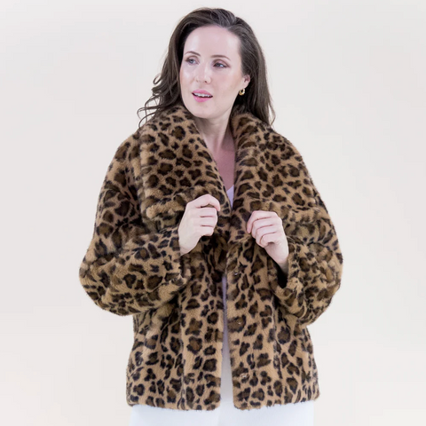Woman wearing a leopard print coat against a plain background