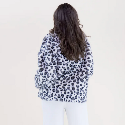 Person wearing a leopard print jacket on a plain background