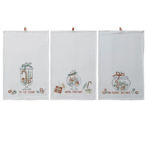 Three white towels with Christmas-themed designs hanging on a line.