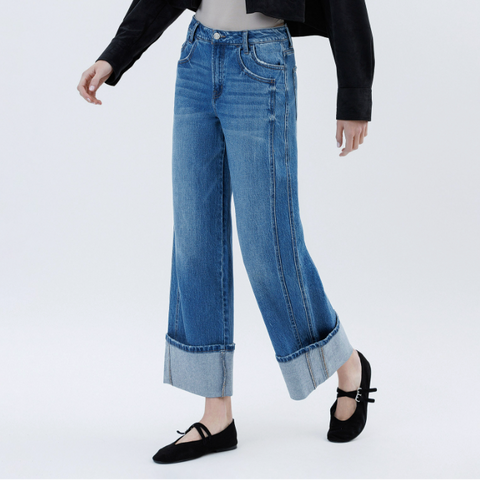 Person wearing blue jeans, black jacket, and black shoes on a white background