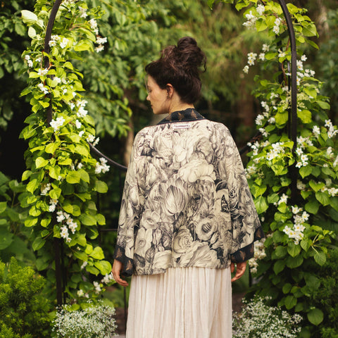 Woman standing under a floral archway in a garden setting